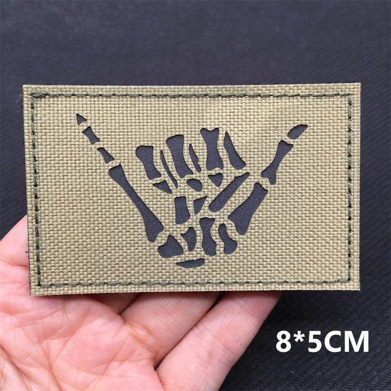 A rectangular olive green tactical patch featuring a black silhouette of a clenched fist.