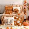 A set of vintage fall pumpkin pillow covers in orange and white on a beige sofa.