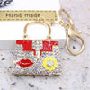 A gold-toned handbag keychain featuring red and white crystal rhinestones with a prominent lips design.