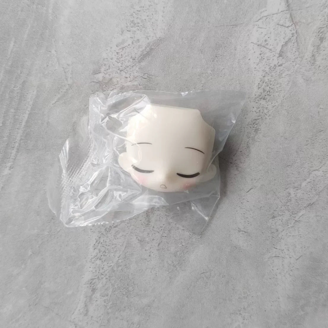 A white articulated ball-jointed doll figurine is sealed in a clear plastic blind box bag.