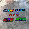 Set of four colorful KYB racing suspension fork stickers on a gray surface.