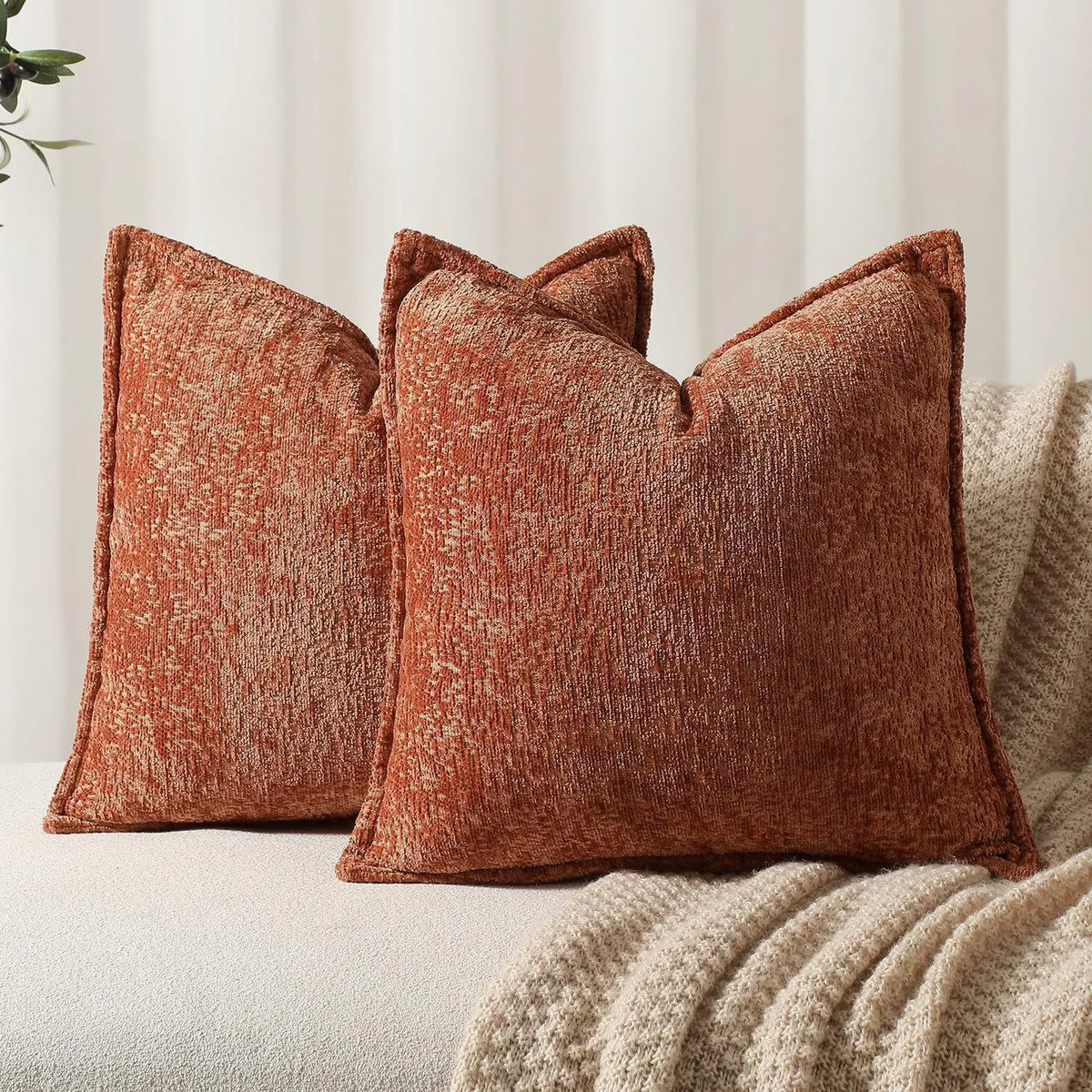 A close-up of a textured, rust-colored chenille throw pillow in a modern farmhouse style.