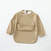 A beige waterproof long-sleeve art smock for toddlers with a pocket on the chest.