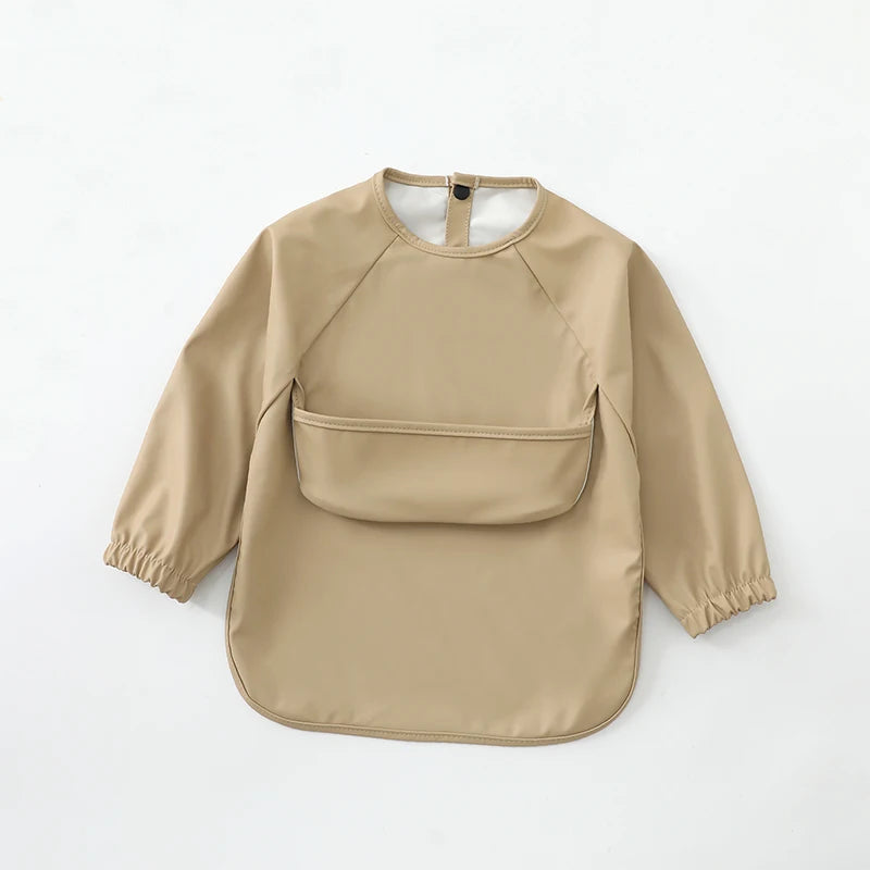 A beige waterproof long-sleeve art smock for toddlers with a pocket on the chest.
