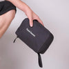 A hand is holding a black hanging travel toiletry bag with the text Travel Season on it.