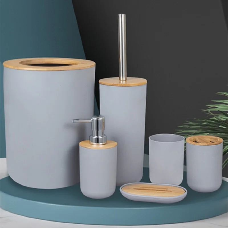 A set of bathroom organizers made of gray ceramic and bamboo, including a soap dispenser and storage containers.