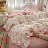 A pink floral duvet cover set with matching pillowcases and a flat sheet is displayed on a bed.