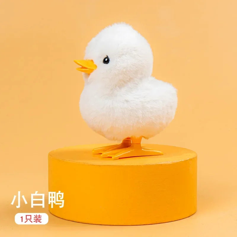 A small white ceramic wind-up walking chicken toy with an orange beak standing on an orange base.