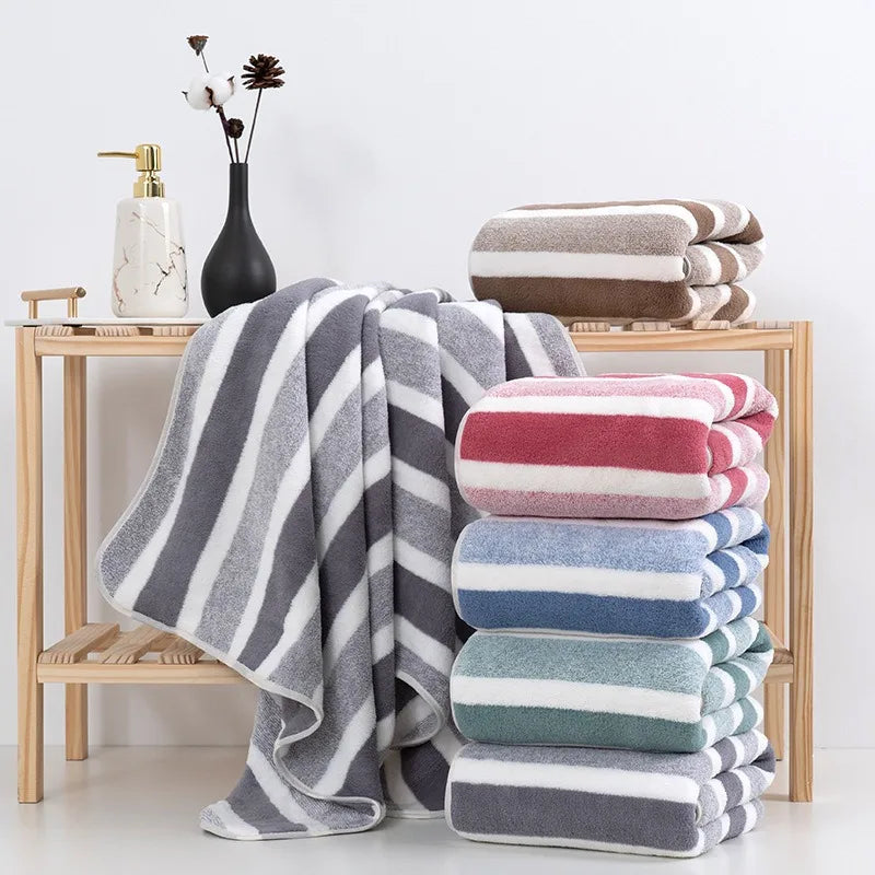 A stack of gray and white striped microfiber bath towels displayed on a wooden shelf.