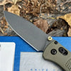 A gray CPM-20CV folding pocket knife with a drop point blade resting on a blue surface.