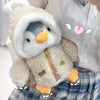 A fluffy white penguin plush toy wearing a hood and featuring orange feet, held against a plaid skirt.