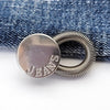 Silver extender buttons attached to a denim fabric strap.