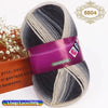 A skein of gradient dyed wool blend yarn in shades of gray and white, packaged with a label.