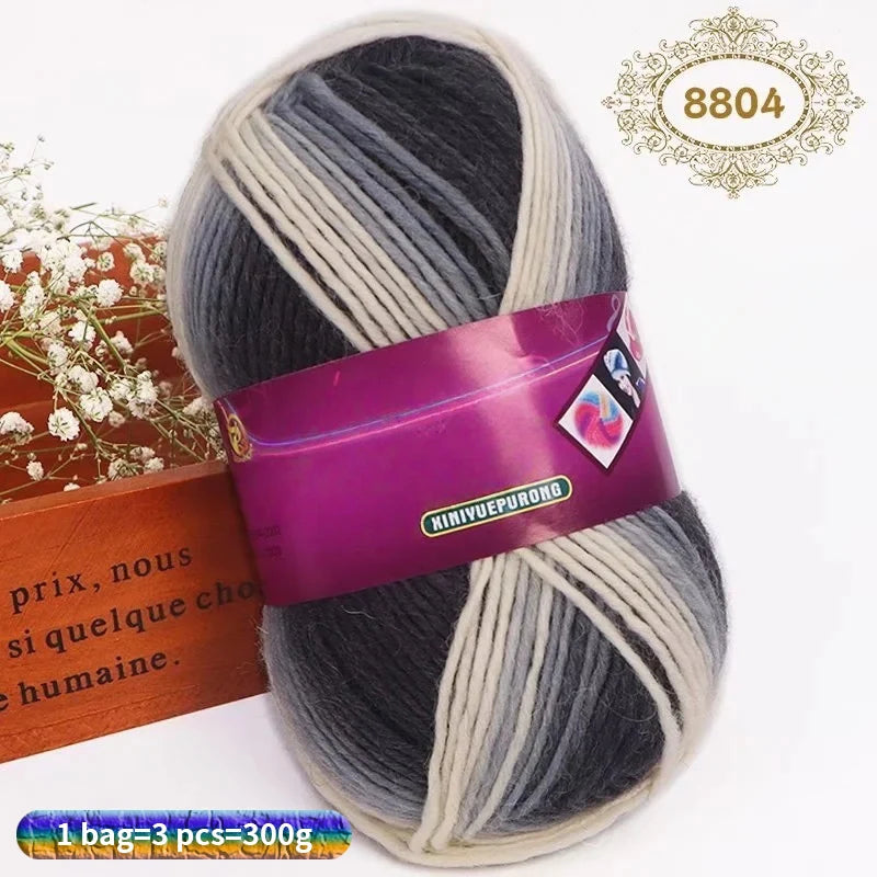 A skein of gradient dyed wool blend yarn in shades of gray and white, packaged with a label.
