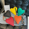 A collection of heart-shaped PU coin purses in yellow, green, and orange resting on a denim shirt next to a book.