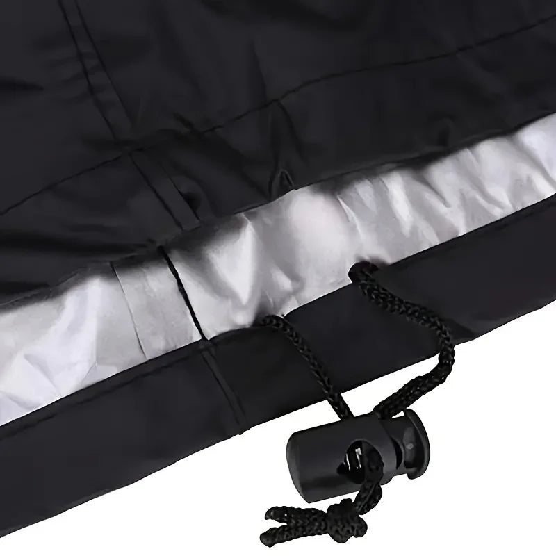 A black heavy-duty waterproof grill cover with a silver lining and a drawstring is shown.