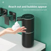 A hand is interacting with a black touchless automatic soap dispenser, showing how it reaches out to create bubbles.