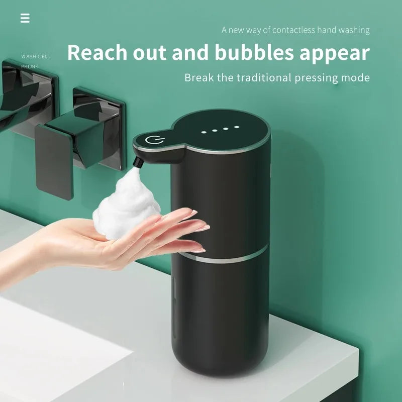 A hand is interacting with a black touchless automatic soap dispenser, showing how it reaches out to create bubbles.