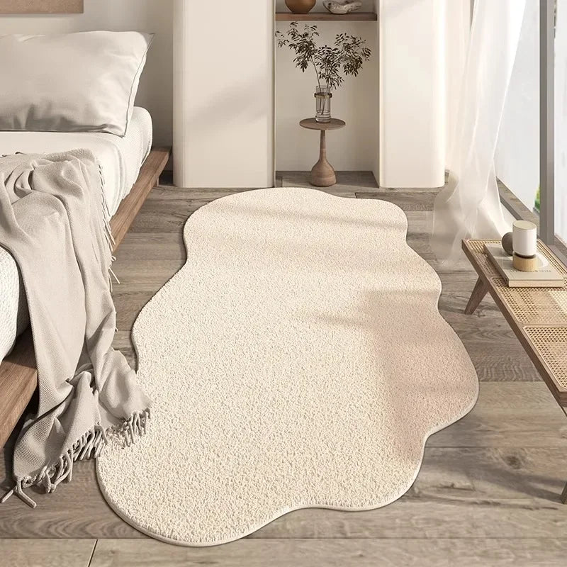 A cream colored irregular area rug with a plush soft texture placed on a light wood floor.