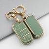 A gold-toned key fob with a green case cover and a decorative ring is shown on a gray surface.