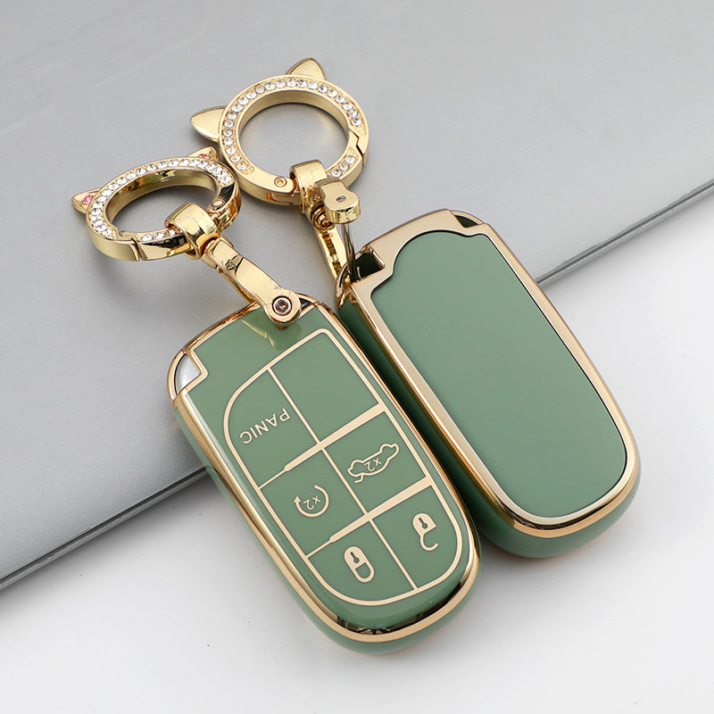 A gold-toned key fob with a green case cover and a decorative ring is shown on a gray surface.