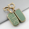 A gold-toned key fob with a green TPU case cover and a keyring is shown on a gray surface.