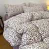 A set of soft printed duvet covers and pillowcases featuring a floral pattern in beige and gray tones.