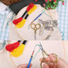 Vintage stainless steel sewing scissors with a chain and embroidery thread on a beige cloth
