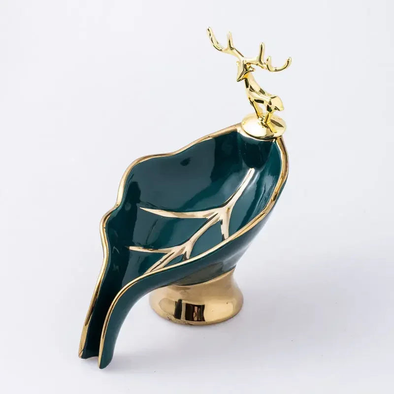A glossy green ceramic soap dish shaped like a leaf with a gold drain rack.