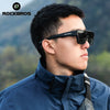 A man wearing black ROCKBROS polarized clip-on sunglasses outdoors against a blurred green background.