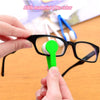 A hand is holding a green cleaning brush attached to a white microfiber cloth, demonstrating the cleaning tool for glasses.