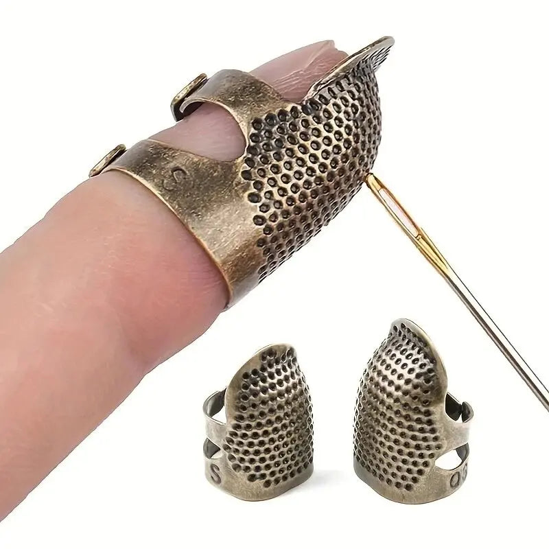 A vintage metal sewing thimble with a finger protector ring is shown being held by a hand.