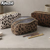 A brown leopard print double-zip pencil case with a gray lining is shown on a light surface.