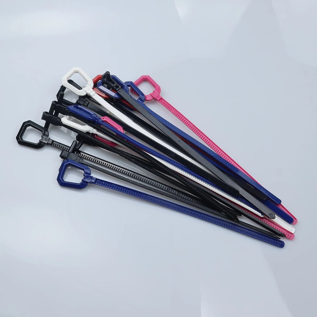 A collection of five replacement ripcord rulers or calipers in various colors, including black, white, blue, and pink.