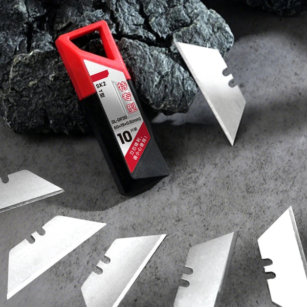 A red and black utility knife with a blade is shown next to several silver replacement knife blades on a gray surface.
