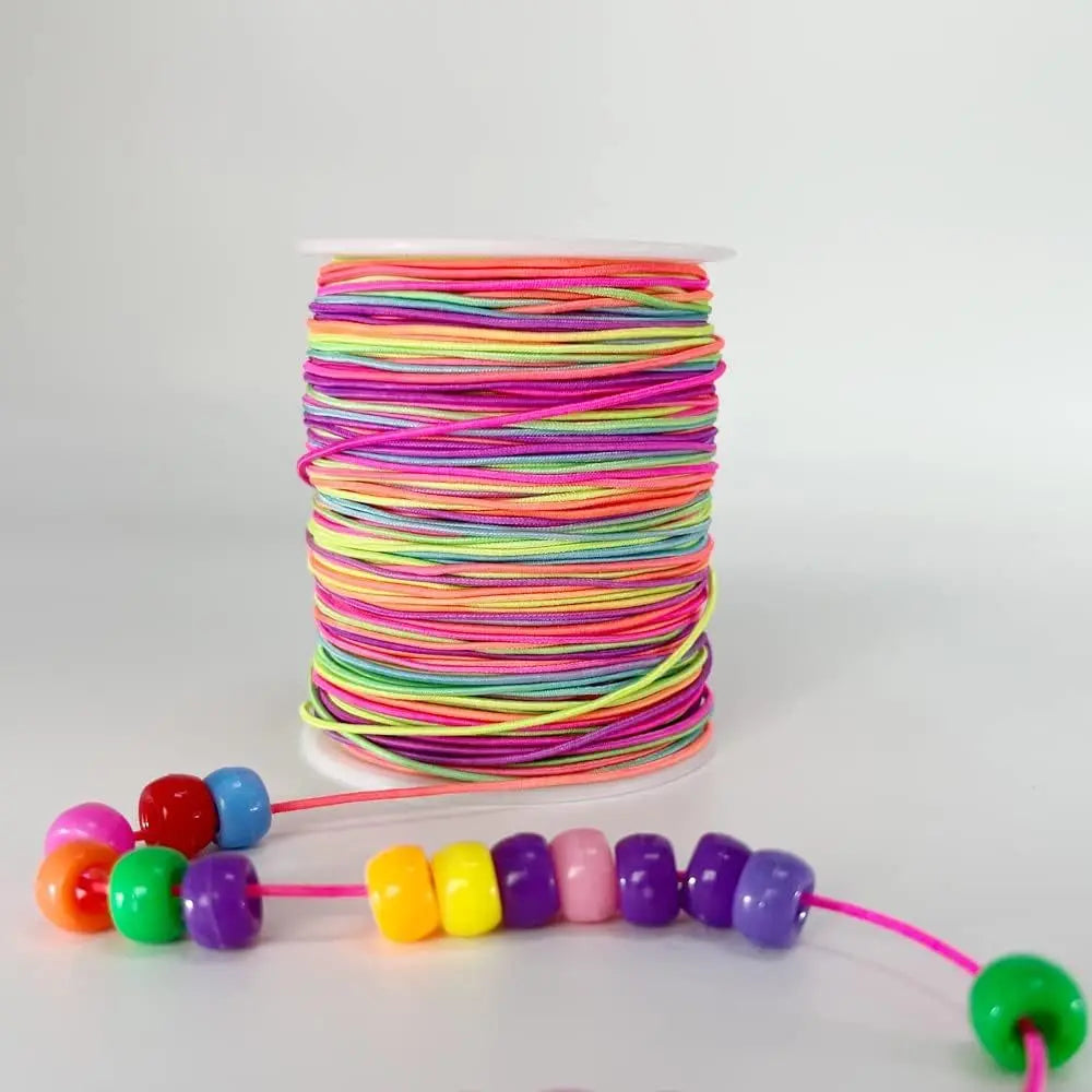A spool of brightly colored rainbow elastic cord, with a length of the same cord stretched out.
