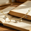 A delicate gold alloy chain with small bow decorations rests on an open book.