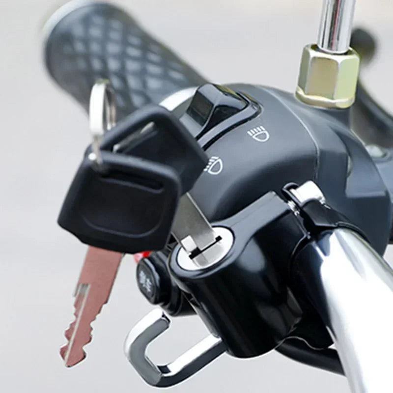 Close-up of a black anti-theft helmet lock mechanism mounted on a bicycle handlebar.