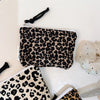 A black and beige leopard print cosmetic bag with a secure zipper displayed on a white surface.