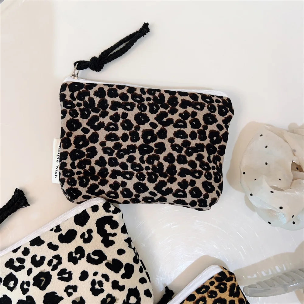 A black and beige leopard print cosmetic bag with a secure zipper displayed on a white surface.