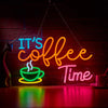 A neon sign shaped like a steaming cup of coffee with the text It's Coffee Time glowing on a dark brick wall.