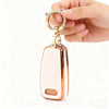 A hand holds a pink gold TPU key fob cover with a circular ring and attached key.