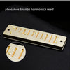 A gold-colored harmonica reed with ten holes shown against a dark background.