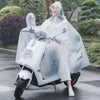 A person wearing a transparent waterproof motorcycle rain poncho with a hood is sitting on a motorcycle on a wet road.