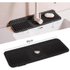 A black silicone faucet splash mat is shown installed in a kitchen sink, featuring a drainer and a soap dish.