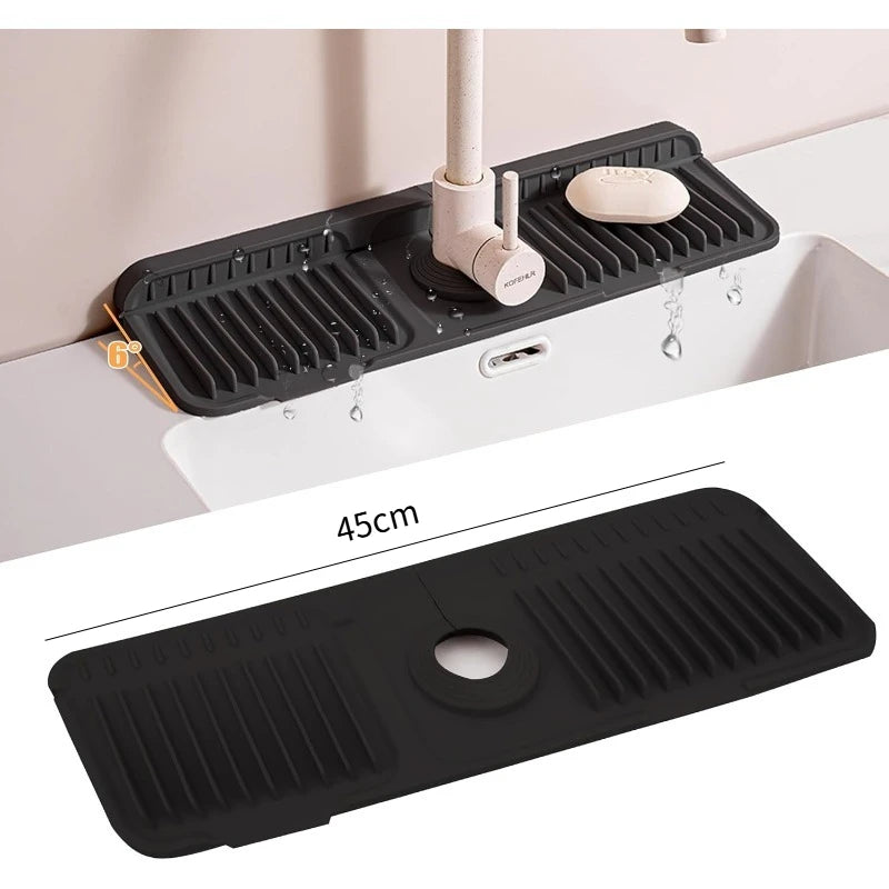 A black silicone faucet splash mat is shown installed in a kitchen sink, featuring a drainer and a soap dish.