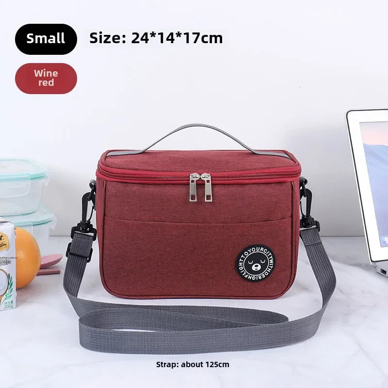 A maroon insulated lunch bag with a gray strap is shown on a white marble surface.