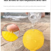 A yellow sticky fruit fly trap ball is dripping liquid onto a glass, set outdoors on a wooden surface.
