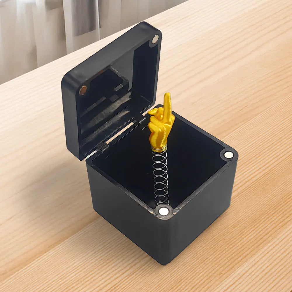 A black box is open, revealing a yellow hand making the middle finger gesture inside.