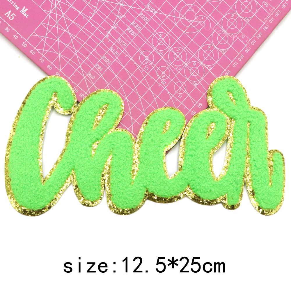 A large green chenille letter patch spelling Cheer with gold glitter outline